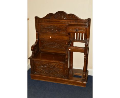 AN EARLY 20TH CENTURY CARVED OAK HALL SEAT/STICK STAND, fitted with a single drawer, the seat with hinged top, lacks drip pan