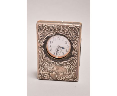 A LATE 19TH CENTURY EASEL BACKED POCKET WATCH FRAME, the white metal mounted front embossed with foliate scrolls and expansiv