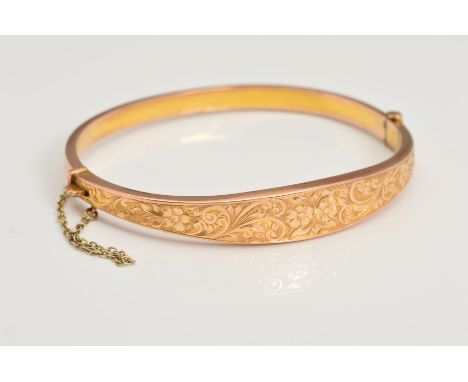 A 1920'S 9CT GOLD HINGED BANGLE, featuring a floral engraved front panel, with a safety chain, with a 9ct hallmark for Birmin