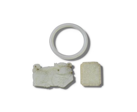 TWO PALE GREEN JADE PLAQUES AND A BANGLELate Qing Dynasty One plaque carved as a luduan with curling horn, its head turned ba