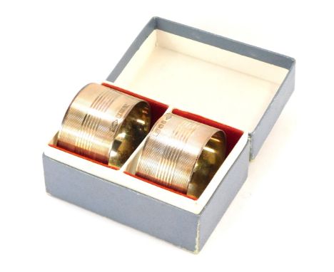 A pair of George VI silver napkin rings, each with engine turned decoration and vacant shield, Birmingham 1945, 1¾oz, in fitt