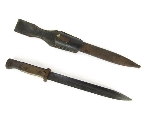 A late 19thC/early 20thC bayonet, with a carved wooden handle and stainless steel blade, with black leather scabbard, with re