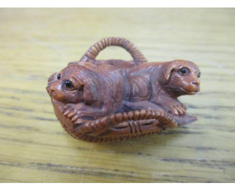A Japanese carved wooden netsuke of two puppies in a wicker basketLocation: Cab 