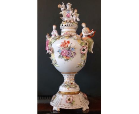 A large Continental porcelain vase and cover, having two putti finial, the vase body adorned with two figures on circular foo