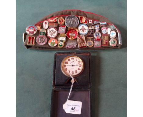 A late 20th century Russian cap, decorated with numerous enamel Russian badges, together with a leather cased travelling cloc