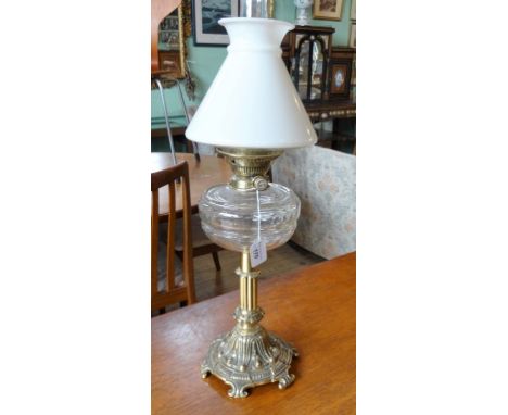 An Edwardian metalware oil lamp, the opaque shade over clear glass reservoir (68cm to include chimney).