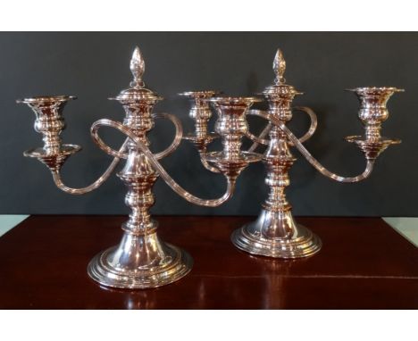 A pair of electroplate on copper, three sconce candlesticks, each with flame finial snuffer (19cm).