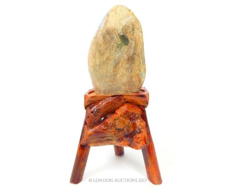 A large uncut jade stone on a rustic wooden stand, total size 62 x 32 x 26cm.