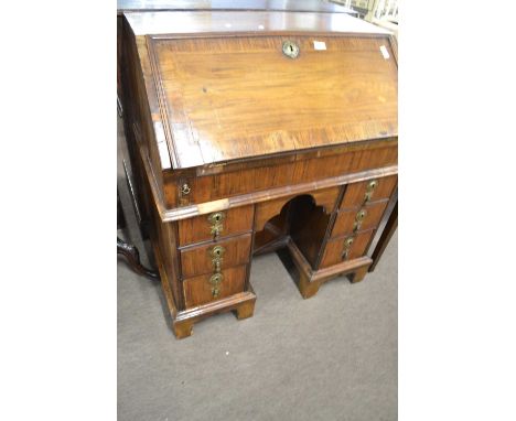 An 18th Century and later walnut knee hole bureau with full front opening to an interior with step and well fitting, the base