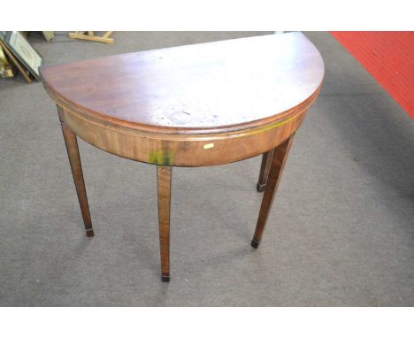 A George III mahogany demi lune card table of typical form with baize lined interior and tapering square legs with spade feet