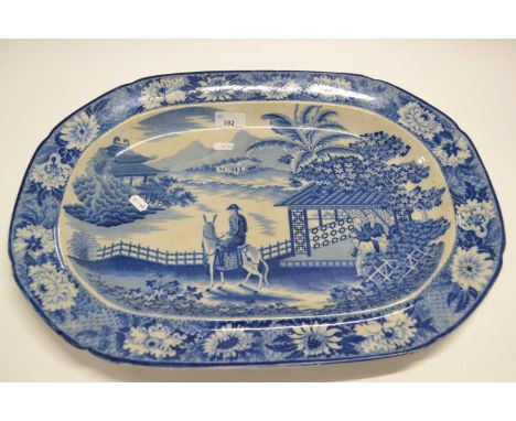 A large pearl ware dish, early 19th Century with blue and white design of a man on horseback with Oriental landscape in the b
