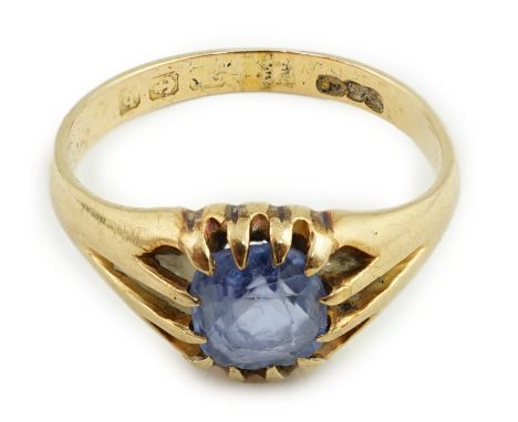 A George V gold and sapphire solitaire ring, the central pale blue emerald cut stone within a claw setting, marks rubbed, siz