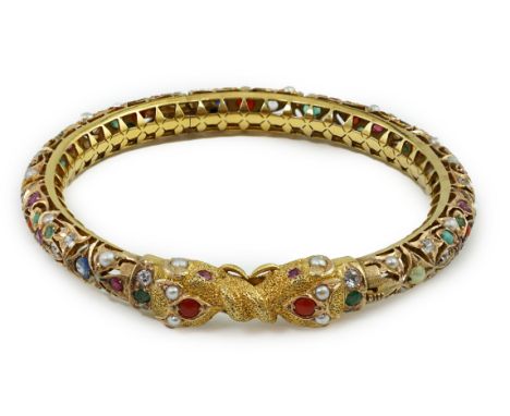 An Indian gold and multi gem set hinged bangle, including sapphires, simulated diamonds, emeralds, rubies and turquoise, with