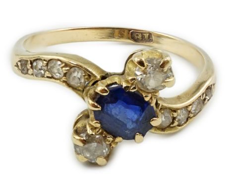 An 18ct gold, sapphire and diamond set three stone crossover ring, with eight stone graduated diamond set shoulders, size O/P