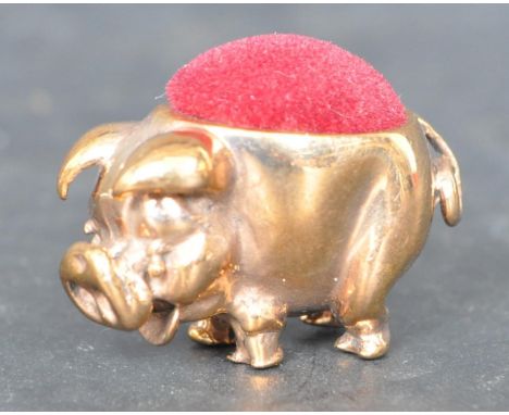 A vintage brass pig pin cushion in the form of a pig with red felt cushion to the back. Measures 3cm in length.&nbsp;