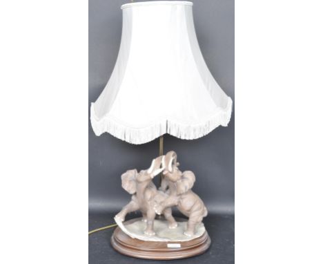 A large 20th century resin cast elephant table lamp and shade. The mahogany base with resin cast scene of fighting bull eleph