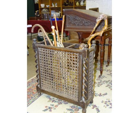 A carved oak three section stick stand and a small collection of walking sticks and canes. 