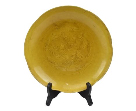 An Imperial yellow-glazed ceramic incised 'dragon' charger plate. The charger with egg yolk yellow glaze, potted with shallow