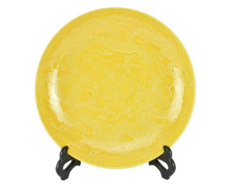 An Imperial yellow-glazed ceramic incised 'dragon' charger plate. The charger with egg yolk yellow glaze, potted with shallow
