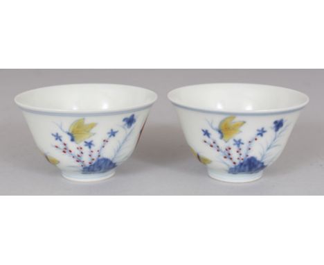 A PAIR OF MING STYLE DOUCAI PORCELAIN CUPS, decorated with butterflies, ferns and rockwork, each base with a six-character Ch