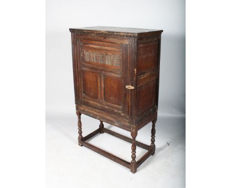 AN 18TH CENTURY OAK CUPBOARD ON STAND, the panel door enclosing a single shelf on a turned base with plain stretchers. 4ft 4i