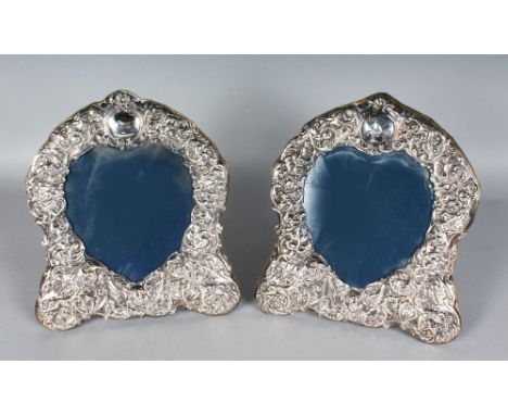 A PAIR OF SHAPED EASEL PHOTOGRAPH FRAMES, with heart shaped centres and winged cupids. London Hallmarks.  11ins high.