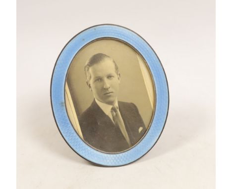 A George V silver and blue guilloche enamel mounted oval easel photograph frame, Goldsmiths & Silversmiths Co Ltd, London, 19