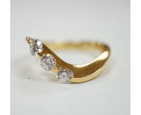 A modern 750 yellow metal and three stone diamond set crossover ring, size P, gross weight 5.4 grams.