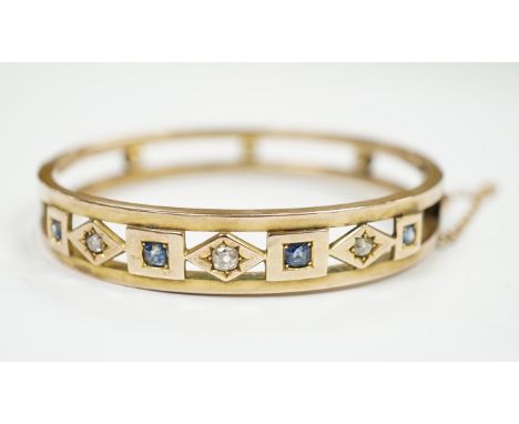 An Edwardian yellow metal, sapphire and diamond set hinged bangle, interior diameter 55mm, gross weight 14.4 grams, with box.