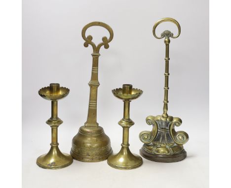 Two 19th century brass door porters and a pair of Gothic Revival brass candlesticks, 37cm (4) Both of the door porters have s