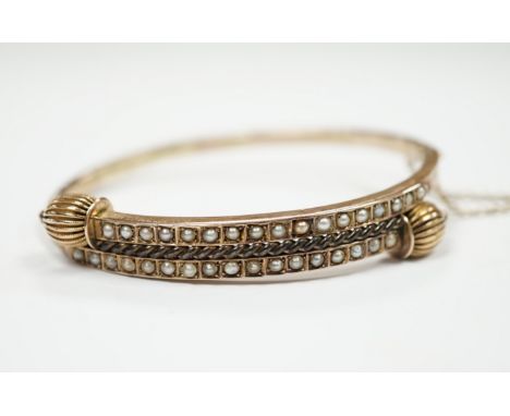 A Victorian yellow metal and two row seed pearl cluster set hinged bangle, gross weight 9 grams.