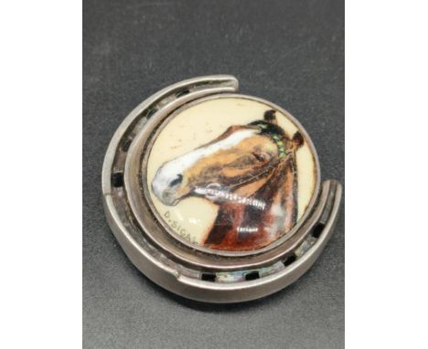 A Sterling silver and enamel painted horse shoe brooch/ pendant. Silver horse shoe having a porcelain enamel plaque to the ce