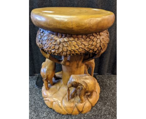 A Hand carved stool made from one piece of trunk. Carved with elephant figures around a tree. [44cm high] 