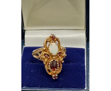 A 9ct ornate ring set with a single opal stone and three garnets. [5.56grams] [Ring size N] [Missing two stones] 