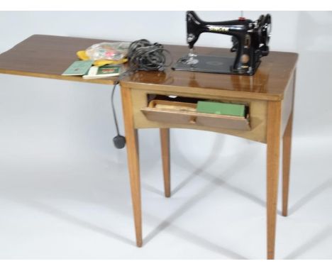 A mid-20thC teak cased freestanding sewing machine, with articulated top and fold-over metal sewing machine with front hinged