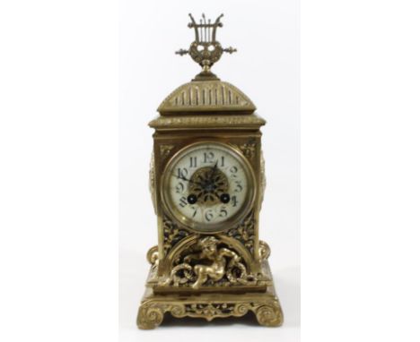 A 19th Century French brass mantel clock, the highly decorative rococo and baroque case with domed top centred by a lyre hold
