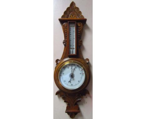 A 20thC oak case barometer and thermometer in heavily carved scroll case, 66cm high 