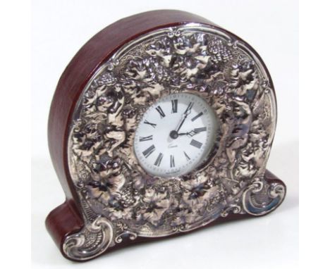 An Elizabeth II silver and leather finish mantel clock, with repoussé decorated front with cherubs and leaves, centred by a R