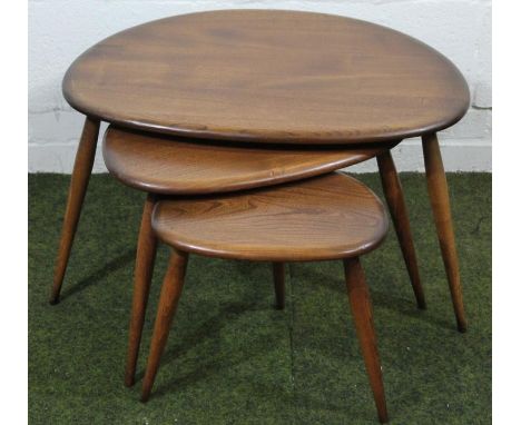 A modern Ercol dark wood retro style nest of three tables, each with shaped oval tops on cylindrical supports, (the largest) 