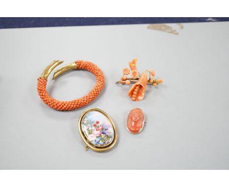 A yellow metal mounted carved coral oval brooch, 30mm, a mounted coral open bangle, a coral brooch and a gilt metal and ename