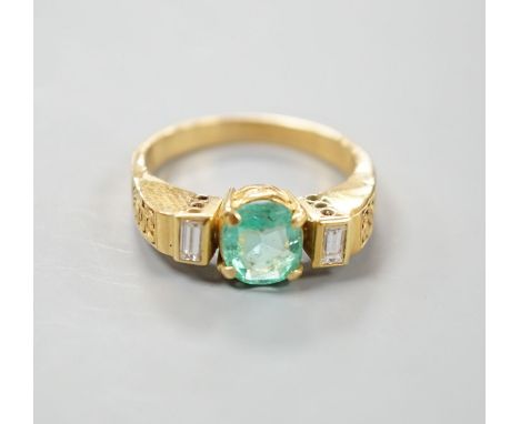 A modern yellow metal,  round cut emerald and two stone baguette cut diamond set dress ring, with pierced shoulders, size Q/R