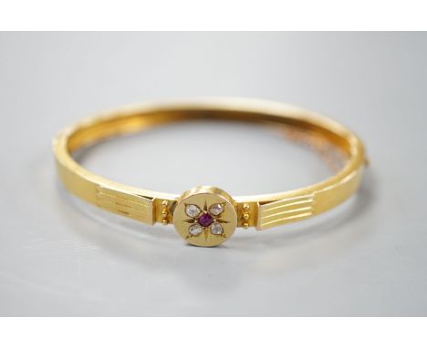 An early 20th century yellow metal, ruby and diamond cluster set hinged bangle, gross 8.9 grams.