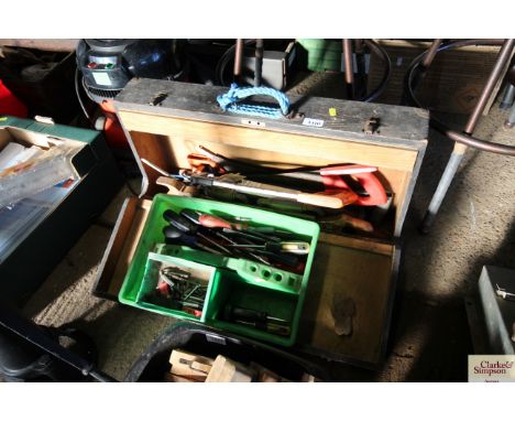 A wooden carpenters tool box containing various hand saws together with a plastic tray of various tools to include screwdrive