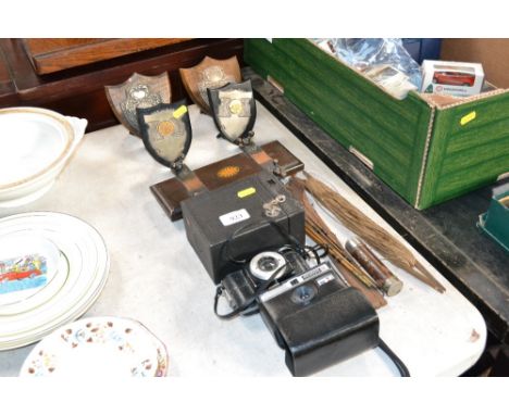 An Instamatic camera, an Ibis camera, tie press, darts trophies, miniature three piece fishing rod etc