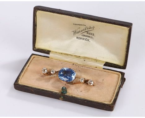 Sapphire and diamond set brooch, the oval light blue sapphire at 5.76 carats flanked by two round cut diamonds to either side