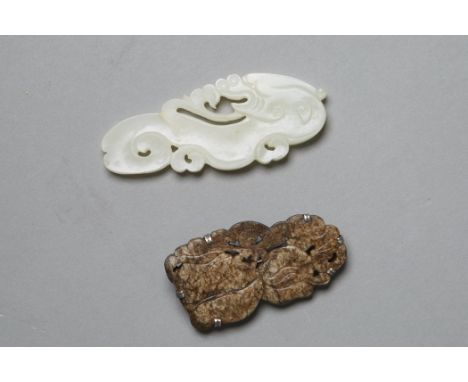 The first pendant shows a swirling cloud transforming into a dragon.  The second object is a pin with fruit on a vine and lea