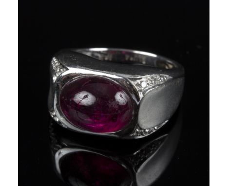 A ruby and diamond dress ring, the oval ruby cabochon set within an oblong stylised 18ct white gold mount, the shoulders set 