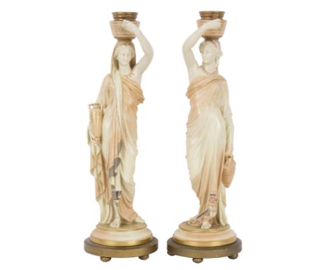 A pair of Royal Worcester blush ivory candlesticks with female figure supports (Grecian water carriers), each holding a vase 