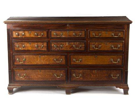 An early 19th century oak mule chest, the hinged cover above six dummy drawers and four long drawers, flanked by reeded pilas