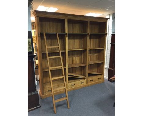 An Oka pine library bookcase, fitted adjustable shelves to the three sections, each with drawer and the ladder and rail for t